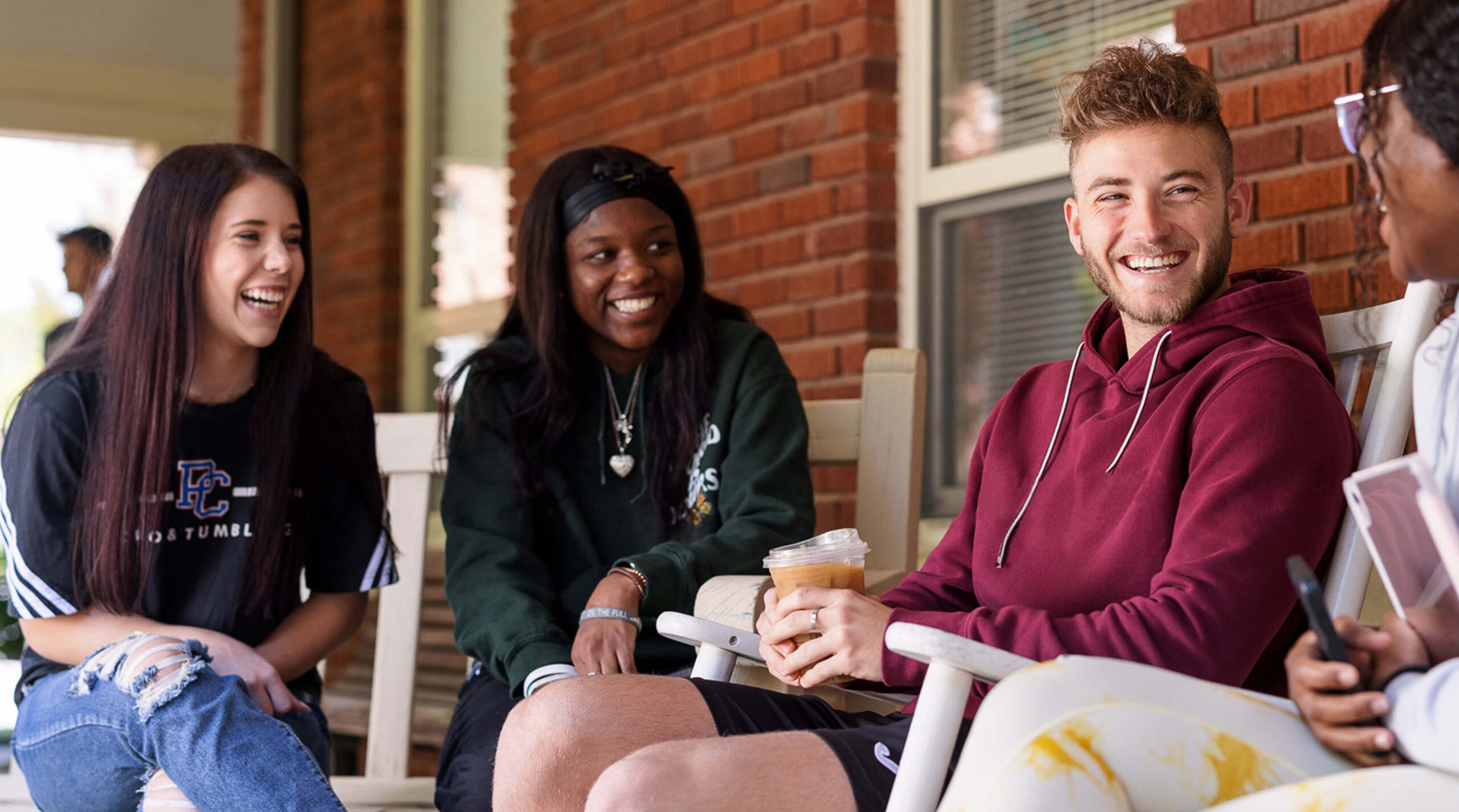 Presbyterian College students sitting in rocking chairs outside of Springs Student Center.