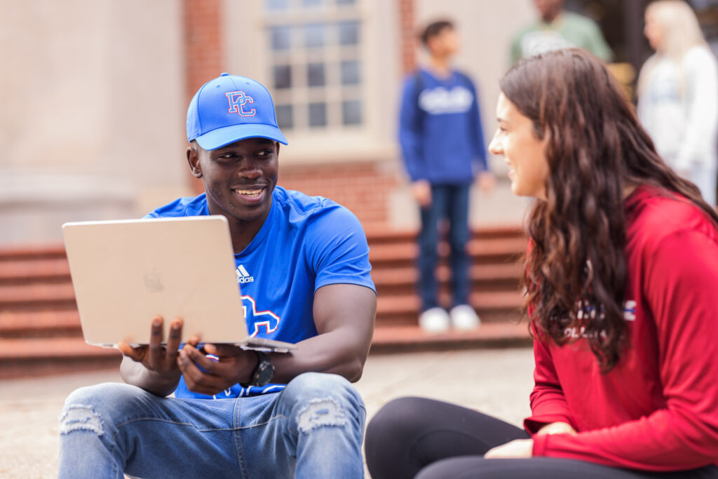 Man and woman using computer and smiling.