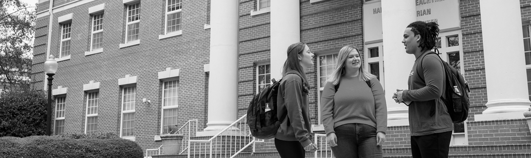Students gathered on campus talking in front of Harrington Peachtree building.