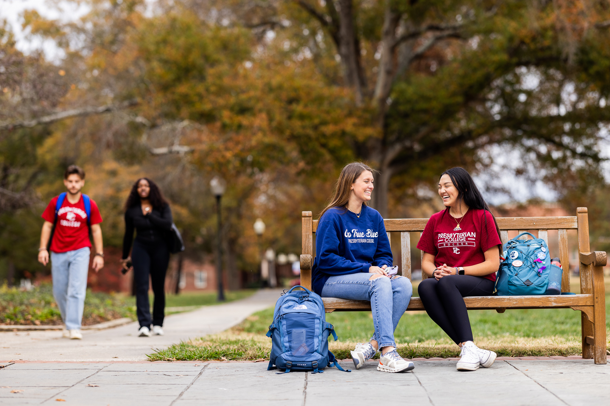 Presbyterian College students sitting on a bench on campus.