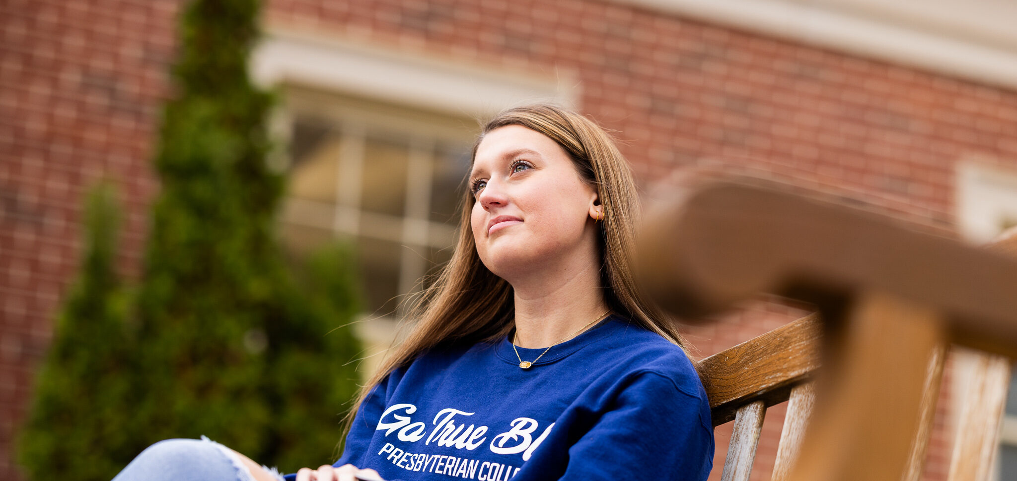 Student smiling sitting on a campus bench.
