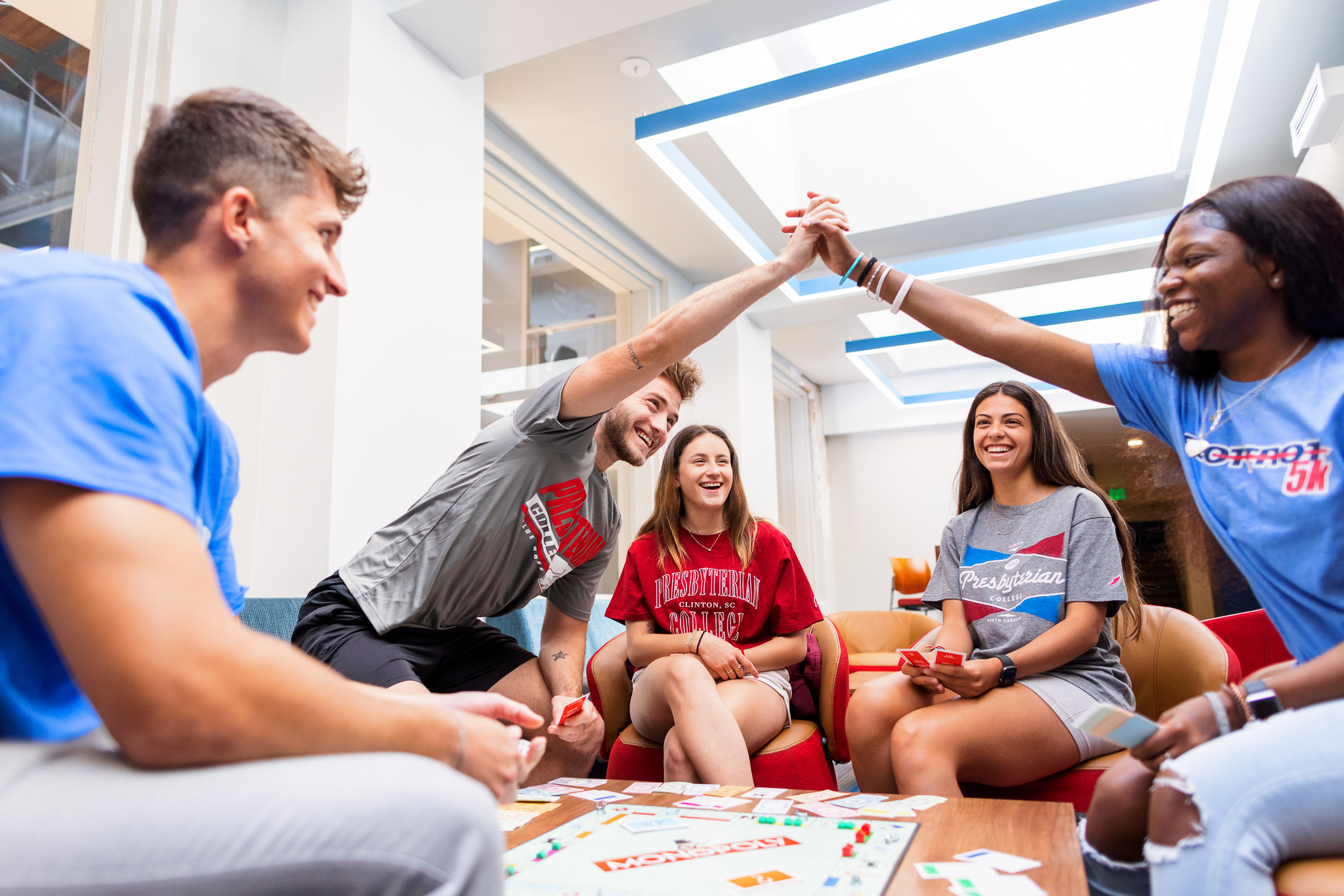 Presbyterian College students high-fiving each other playing a board game in Springs Student Center.