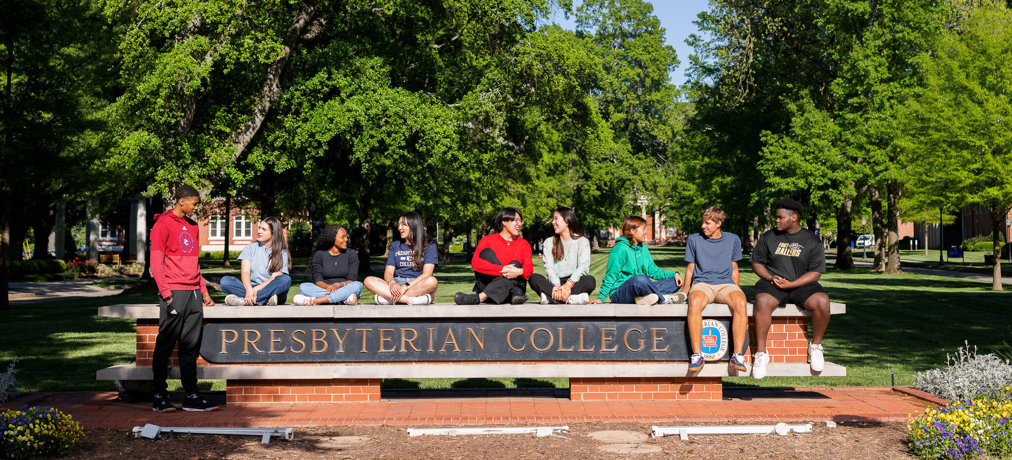 Presbyterian College students sitting on the PC sign.