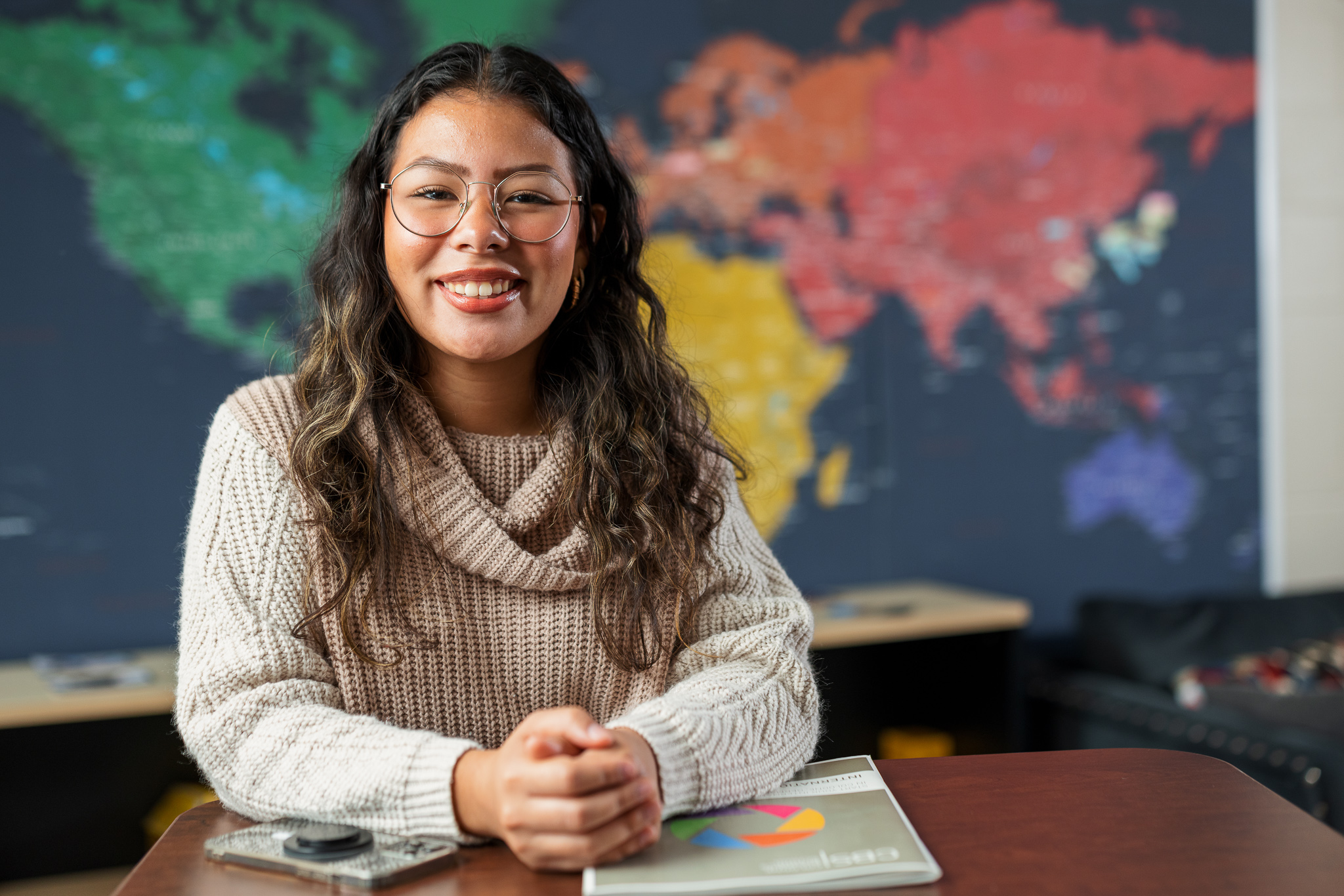 Presbyterian College student smiling with a map in the background.