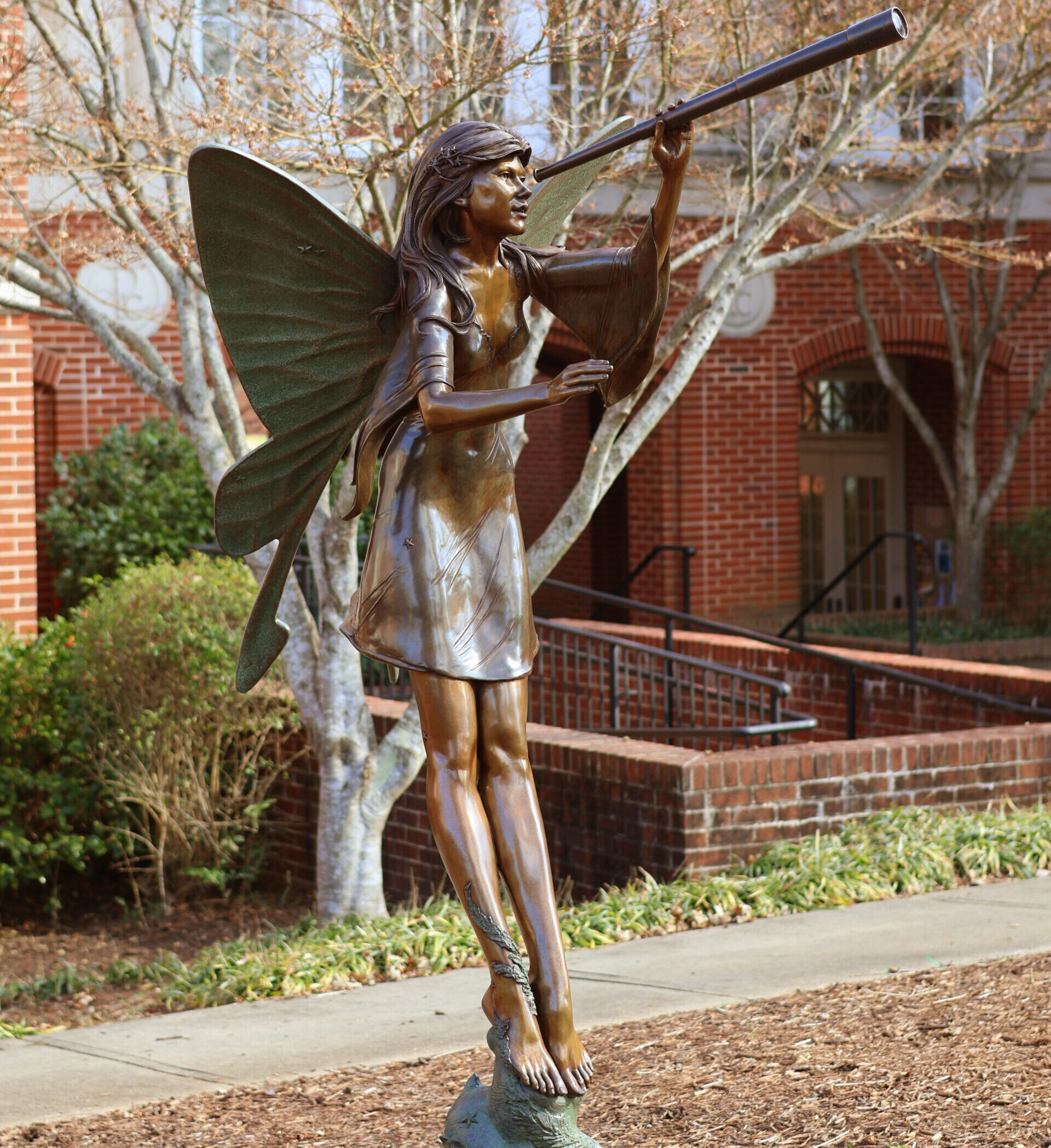 A picture of a statue on campus looking through a telescope.