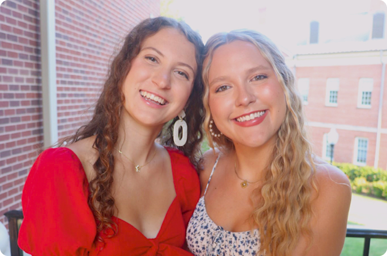 Two PC students smiling for a picture before a Greek event. 