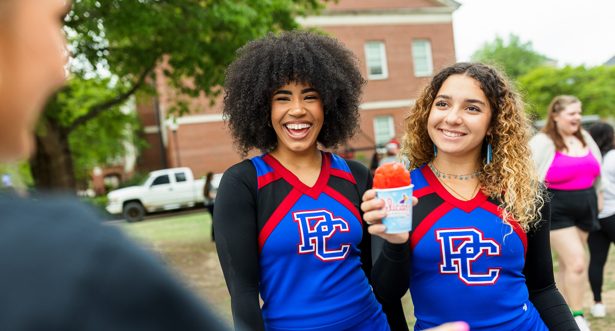 Two PC cheerleaders smiling with a snow cone.